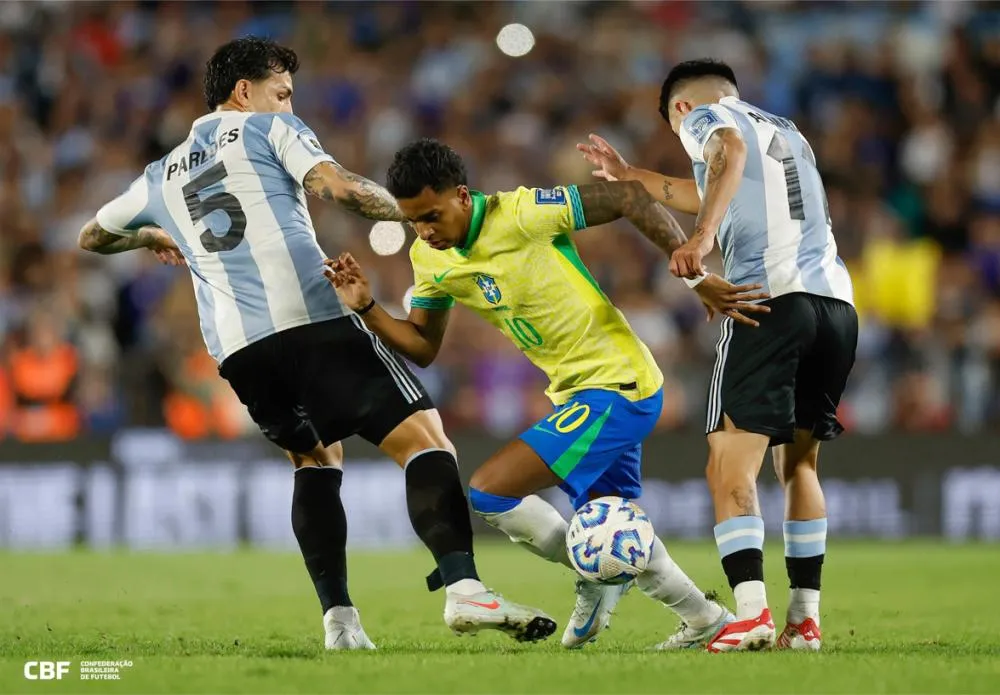 Rodrygo tenta se livrar de dois adversários no Monumental de Nuñez - Foto: Rafael Ribeiro/CBF