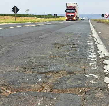 Caminhões trafegam sobre asfalto desmantelado na BR-153: a deterioração da pista simples eleva o risco de acidentes
